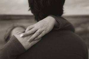 Close-up of hands gently touching in black and white.