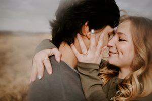 Close-up of an affectionate embrace in a rustic outdoor setting.
