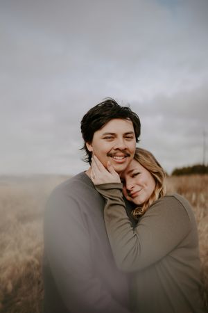 Candid moment of laughter and joy between a couple in warm sweaters.
