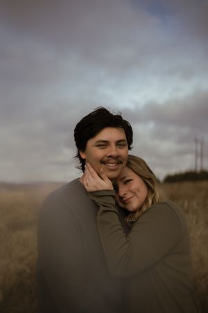 A couple laughs and embraces while enjoying a romantic moment in nature.