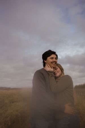 A romantic couple shares genuine laughter and tender moments in an outdoor setting.