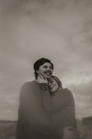 An intimate black and white portrait of a couple sharing a close moment outdoors.