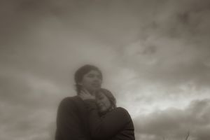 A romantic silhouette of two people embracing under stormy skies.