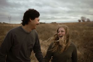Two people enjoying a romantic moment in an autumn field at dusk.
