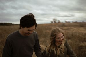 Two people sharing an intimate moment in a golden field under cloudy skies.