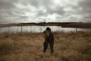 Wide panoramic view of a couple walking hand in hand through a vast autumn landscape.