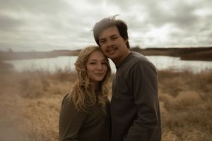 A romantic couple shares an intimate moment in a rustic outdoor setting.