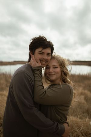 A couple shares joyful laughter while embracing in a natural setting.