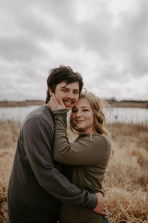 Joyful embrace between couple wearing matching sweaters in autumn field.