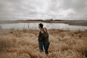 Panoramic view of couple walking through autumn field near water.