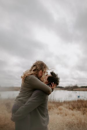 Intimate couple portrait in golden field under cloudy skies.