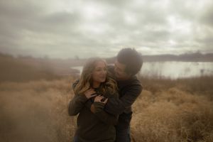 A couple embraces in a dramatic outdoor setting with moody lighting.