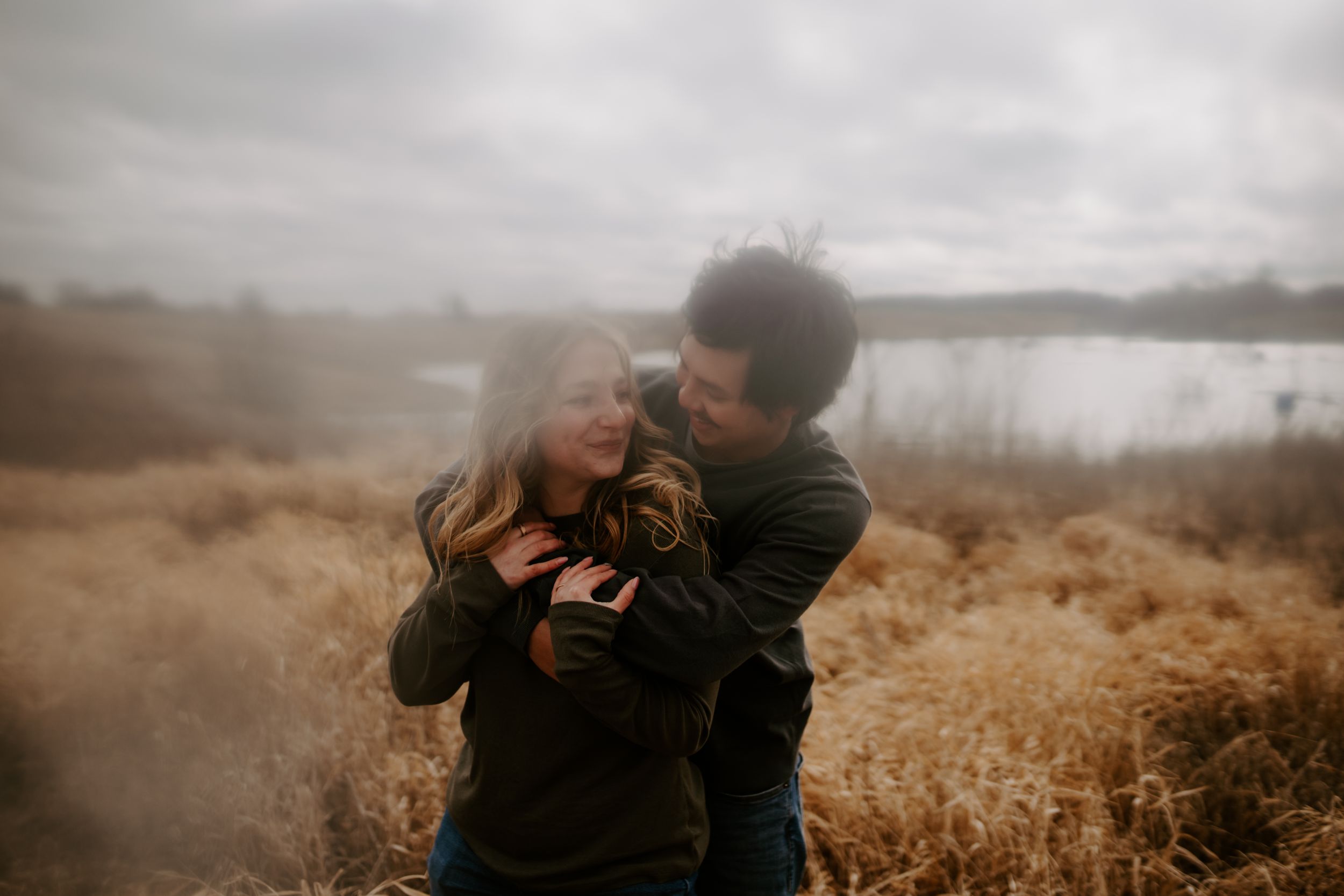 An intimate moment captured between a couple in a golden field during sunset.