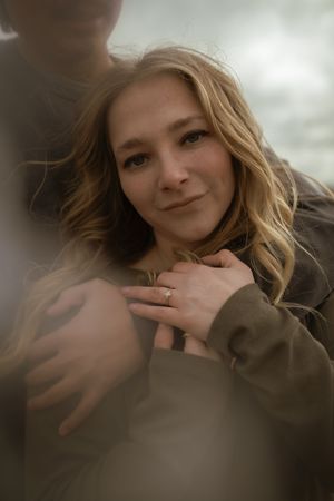 A warm portrait captures a woman's gentle smile as she shows her engagement ring.