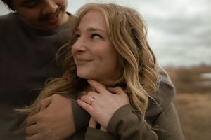 Close-up of couple sharing intimate moment in outdoor setting with dramatic clouds.