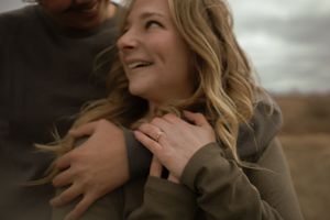 Loving couple embracing in natural setting with moody sky backdrop.