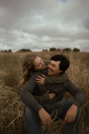 Candid shot of couple laughing together while sitting in autumn field.