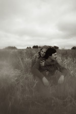Black and white portrait of couple embracing in misty field.