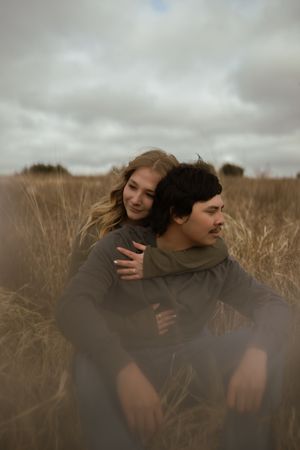 Two people share an intimate moment together in a brown winter field.