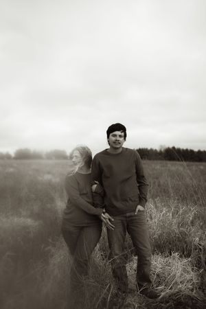 A couple poses together in a sepia-toned field landscape.