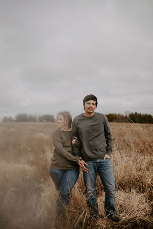 Couple playing and laughing together in autumn field setting.
