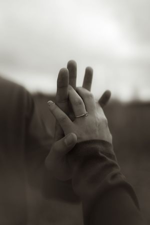 Close-up of hands with a wedding ring against a blurred natural background.