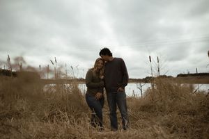 Two people walk together in silhouette across a rural landscape.