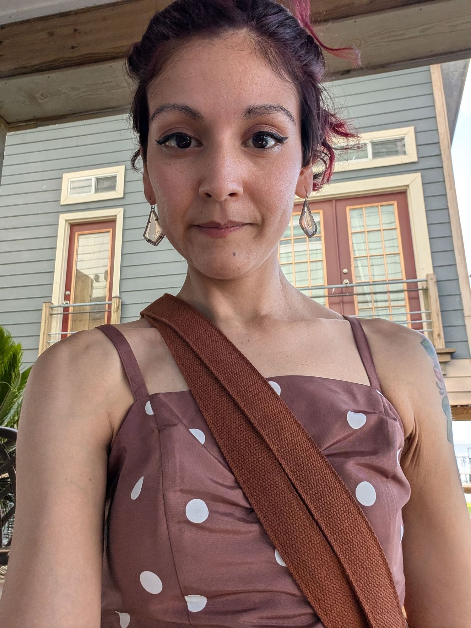 A selfie progression showing a person in a brown polka dot top with burgundy hair smiling at different angles.