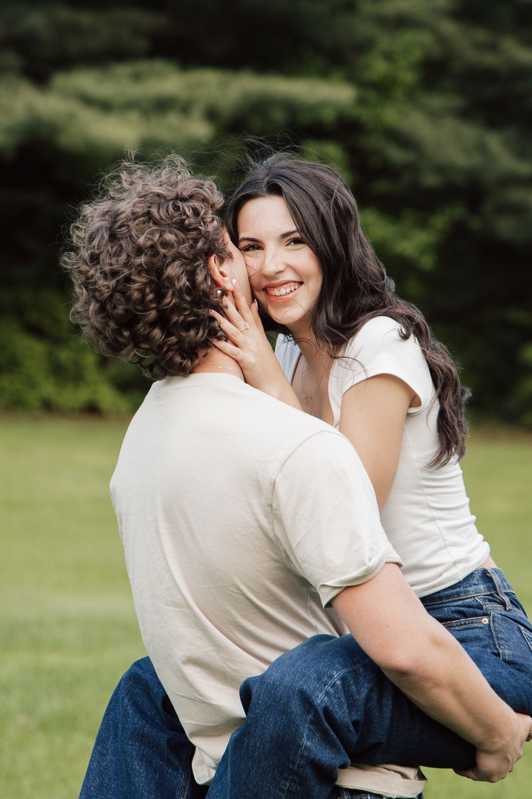 A couple sharing a tender moment together in a grassy park setting.