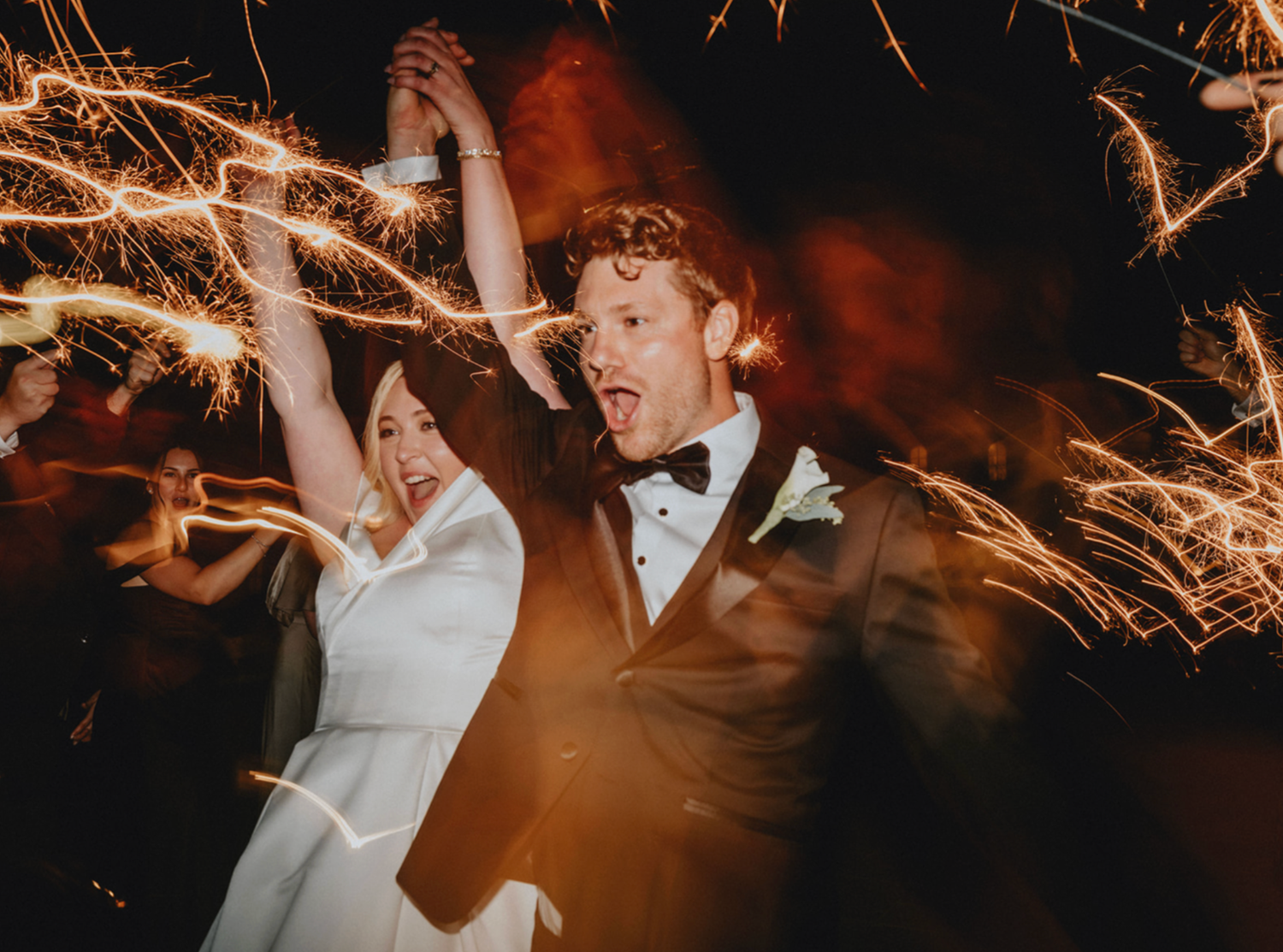 Joyful sparkler exit photo of husband and wife leaving The Tannery Barn wedding venue in Mount Airy, Maryland.