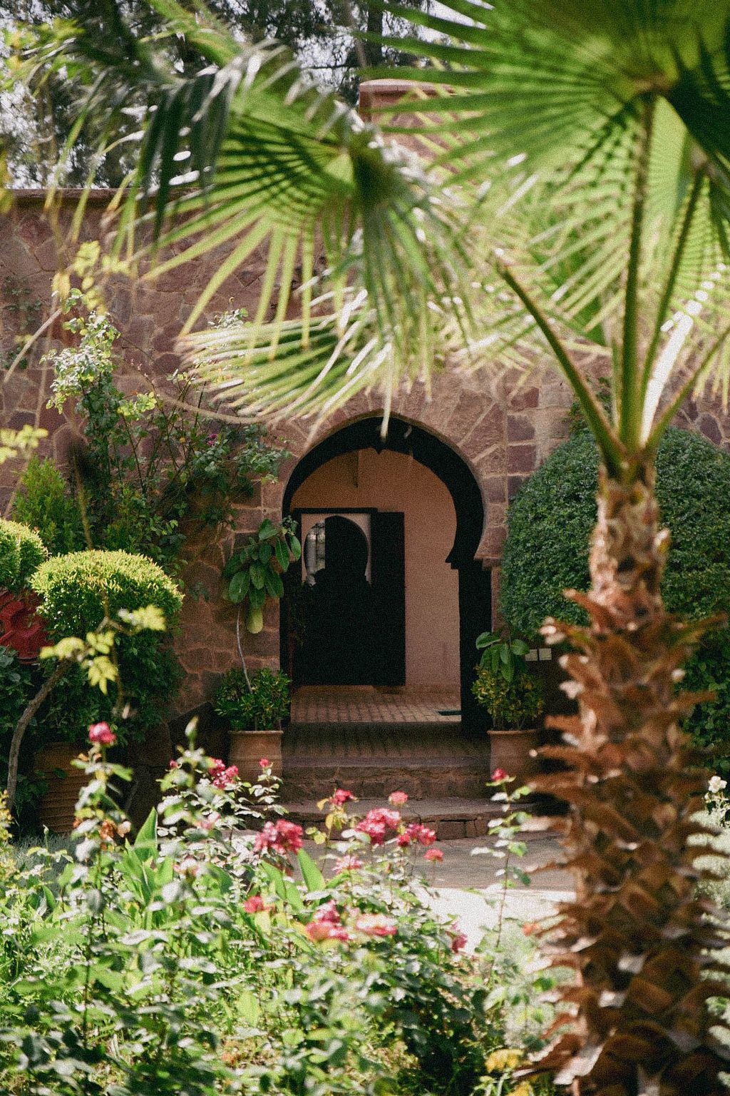 Entrée verdoyante de Bab Zouina, havre de paix niché au cœur d’un jardin luxuriant près de Marrakech.