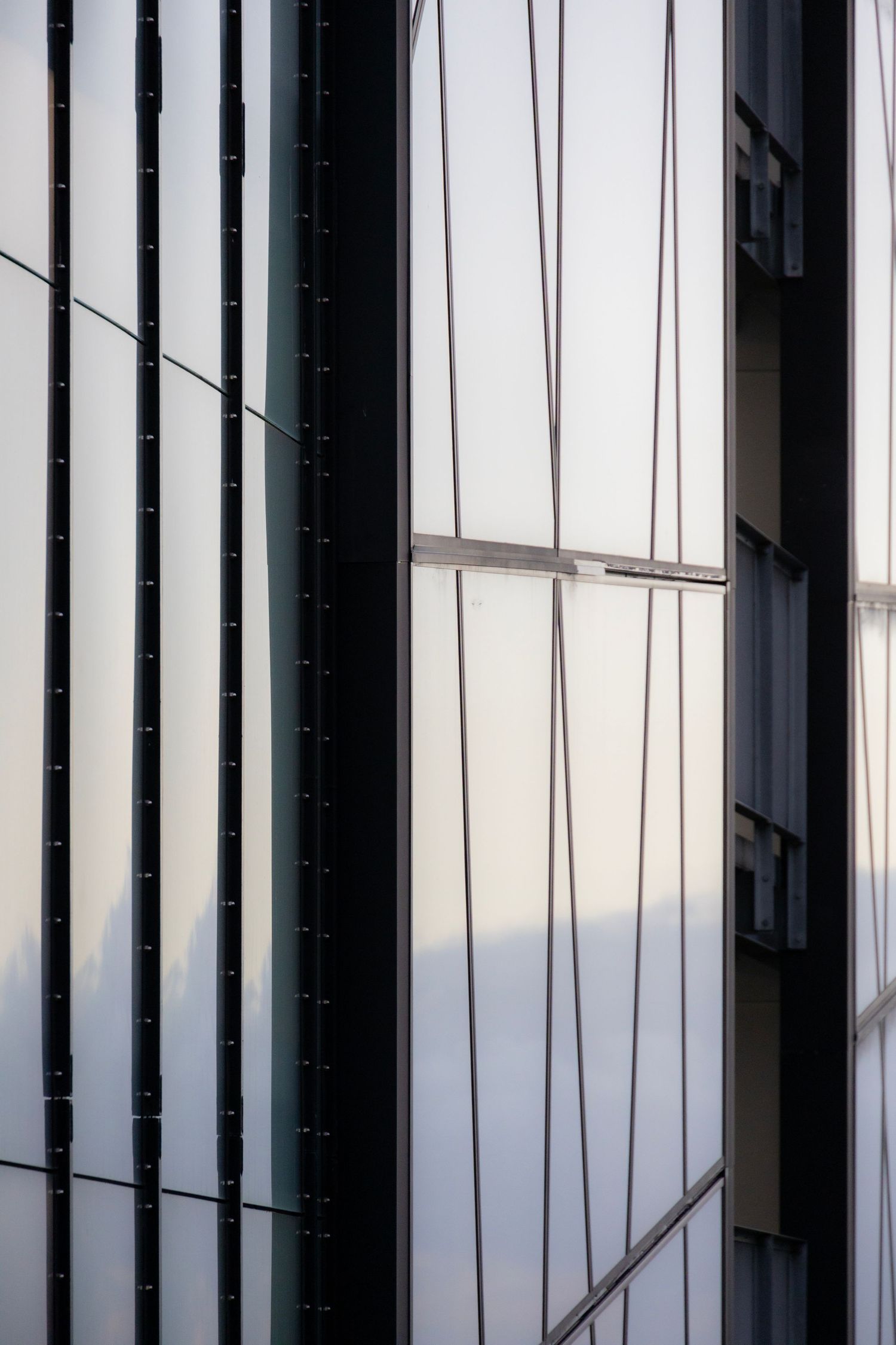 Minimalist facade with translucent panels catching golden light and faint landscape reflections.