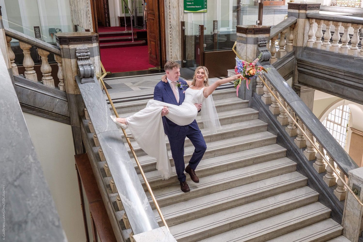 Wide marble staircase with ornate railings in a grand historic building or venue.