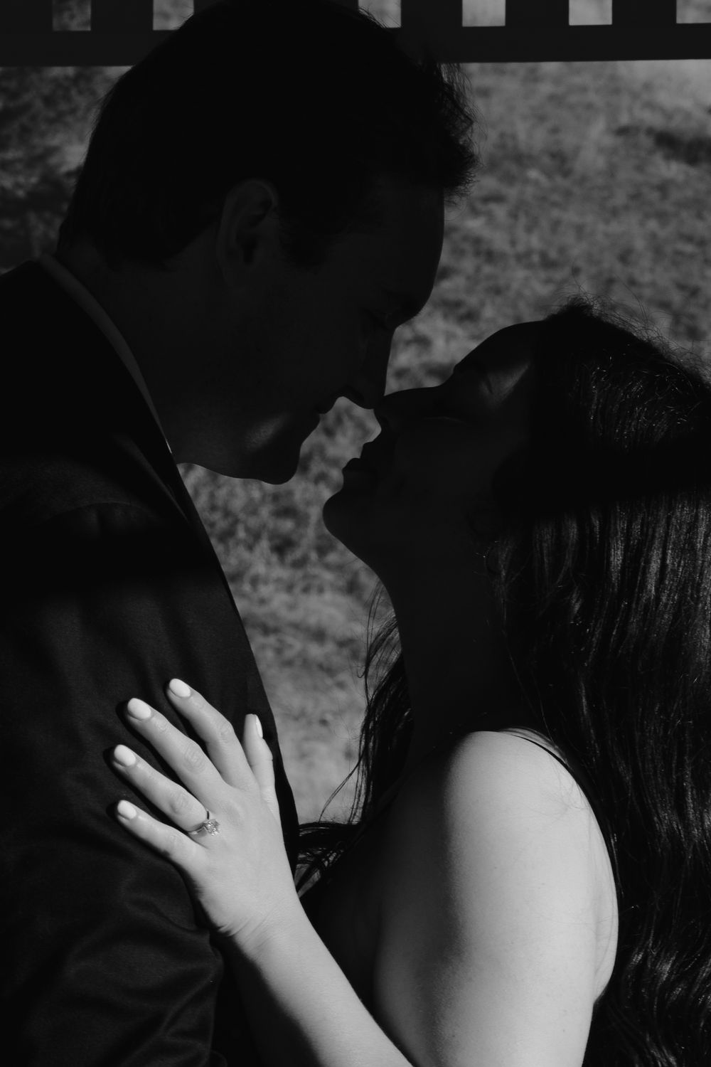 Intimate black and white photo of a romantic couple sharing a tender moment outdoors.