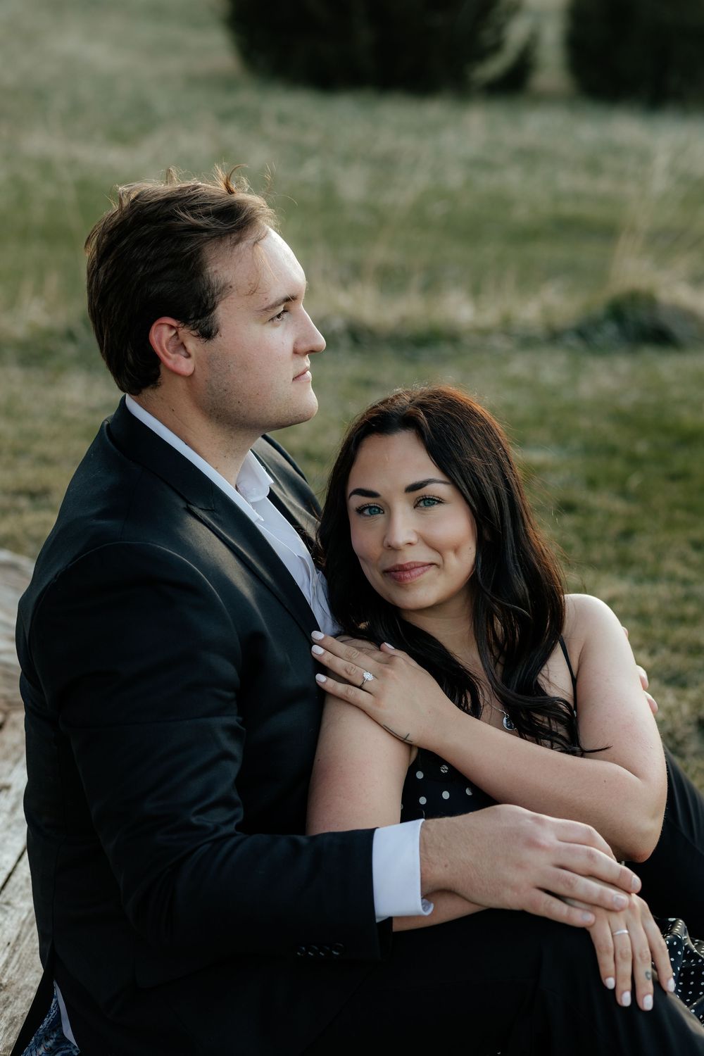 A romantic outdoor portrait of a couple embracing in a natural setting during golden hour.
