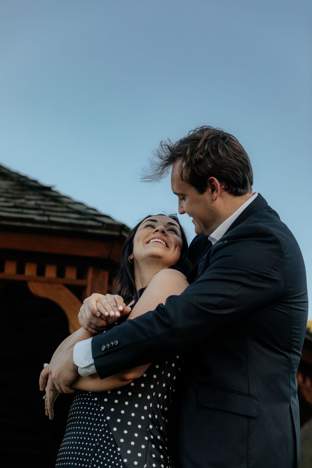 A couple sharing an intimate moment in front of a rustic building during blue hour.