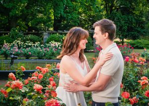 A happy moment shared between partners embracing in a summer garden filled with vibrant pink roses and lush greenery.