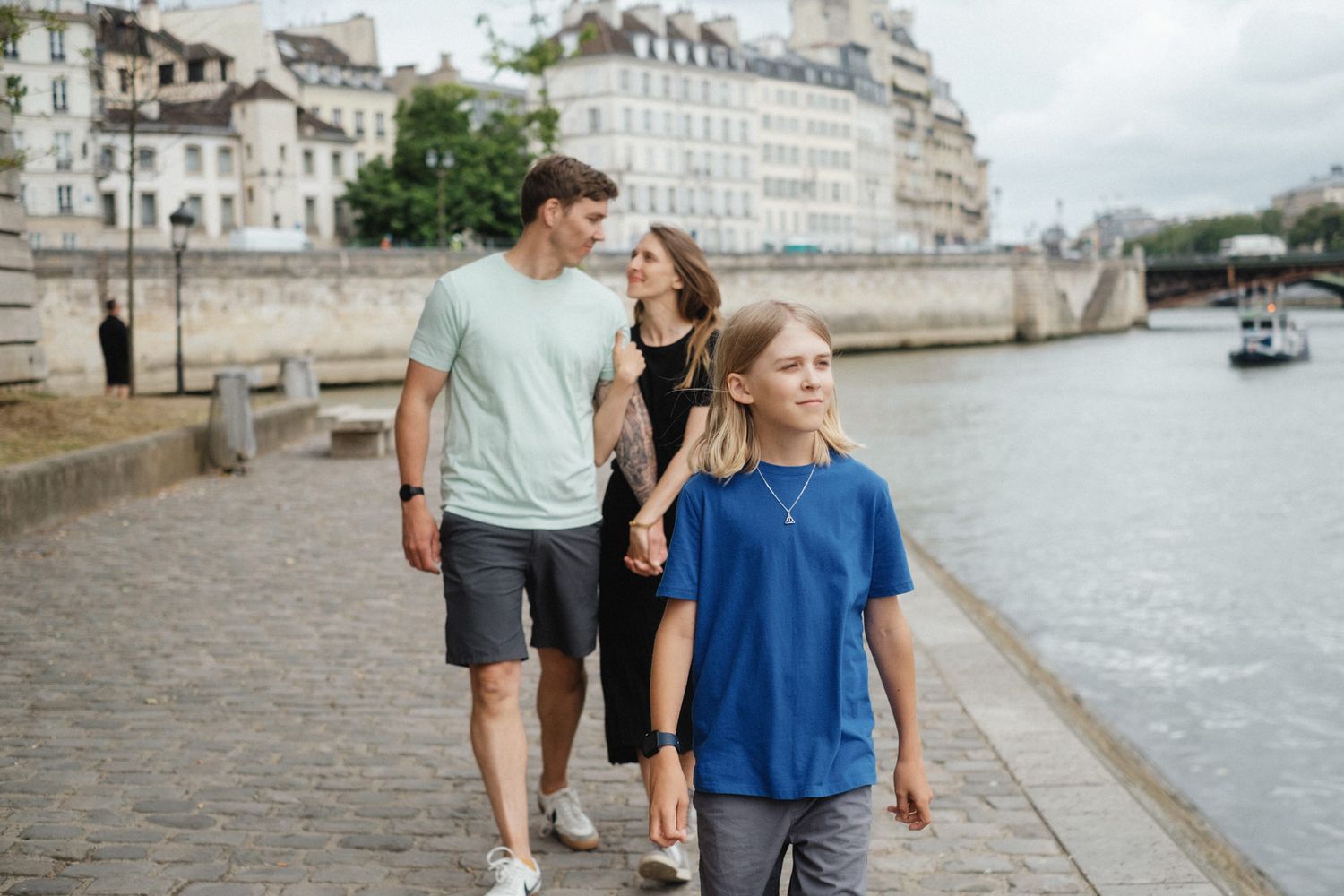 Couple walking together along a cobblestone path by the riverside during an overcast day.