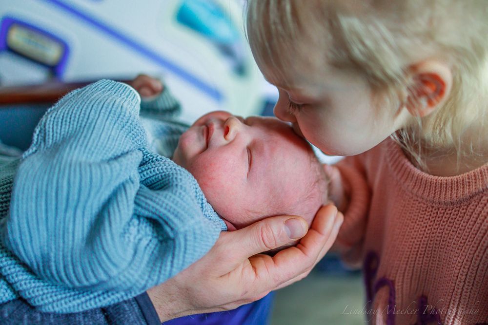 Close-up of baby's face while being held in knit sweater.