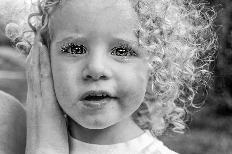 Black and white close-up portrait of a young girl with curly hair and expressive eyes.