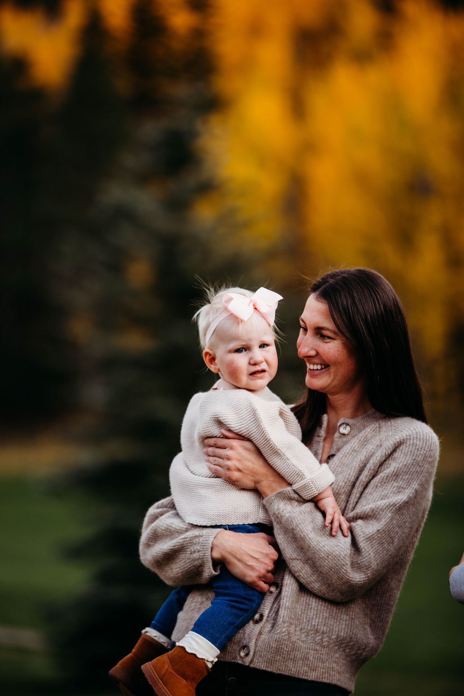 A heartwarming moment captured against golden autumn trees as family members embrace and laugh together.