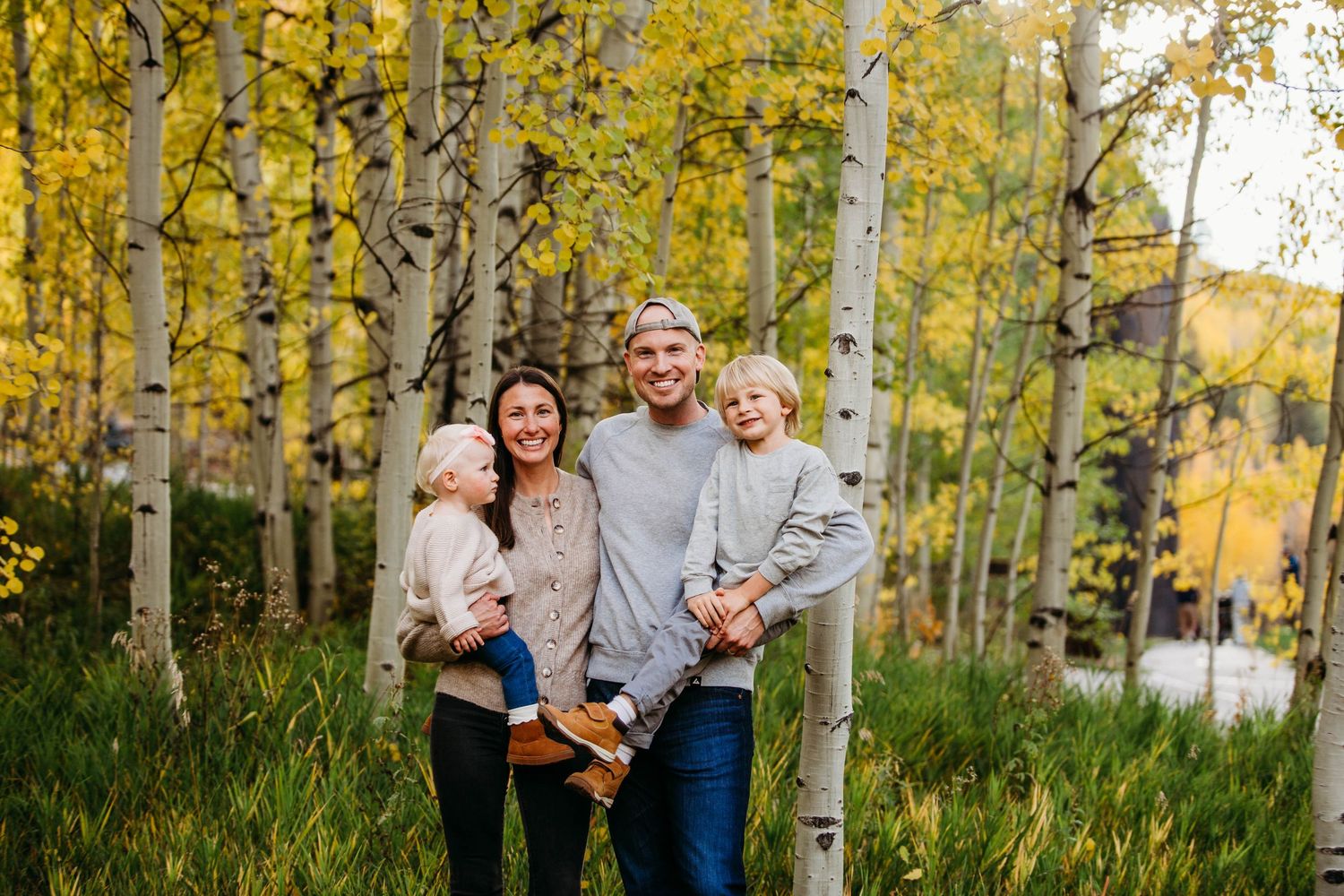 A group stands together against a backdrop of golden aspen trees in autumn.