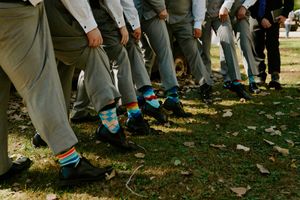 Wedding party members showing off their colorful socks in a fun outdoor group photo.