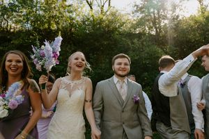 Wedding party members sharing laughs and smiles during outdoor photo session.