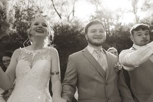 Black and white photo of wedding party members laughing together outdoors.