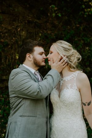 Romantic moment between newlyweds in gray suit and lace wedding dress.