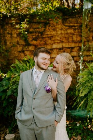 A joyful wedding moment captured against a rustic stone wall with lush greenery.