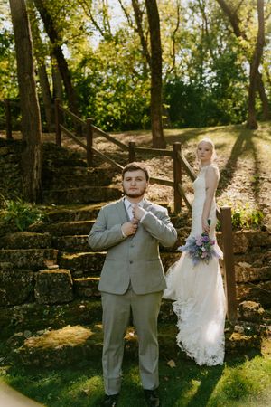 Playful wedding photos taken against stone wall backdrop in natural sunlight.