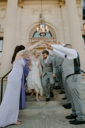 Fun group photos on steps of stone building with wedding party in purple and gray.