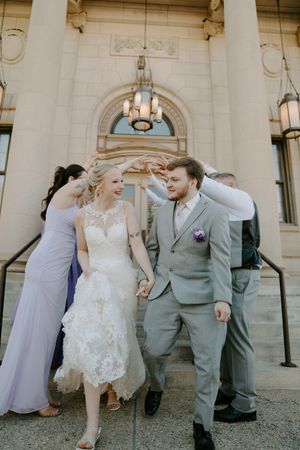 Candid moments of wedding party laughing together outside historic building.